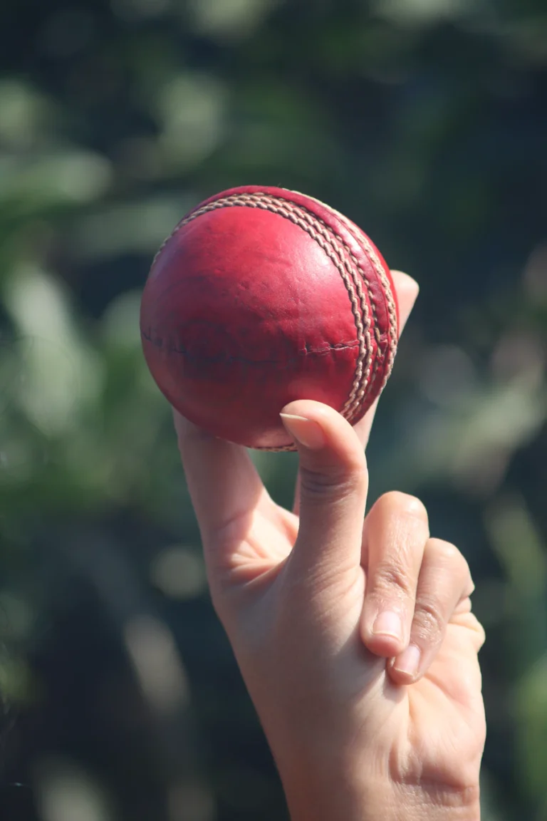 Hand holding up a red cricket ball